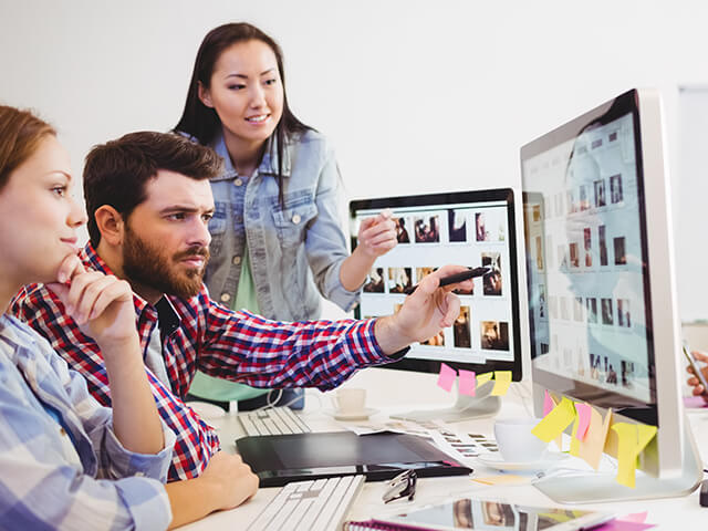 People partnering to create and edit creative materials on an iMac
