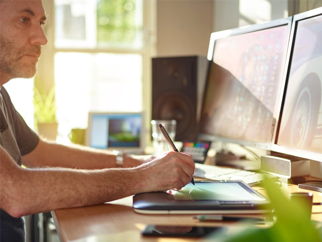 Man at computer drawing digital creative and design work with a stylus on a tablet