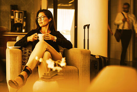 A woman sits drinking coffee in a hotel undergoing application transformation