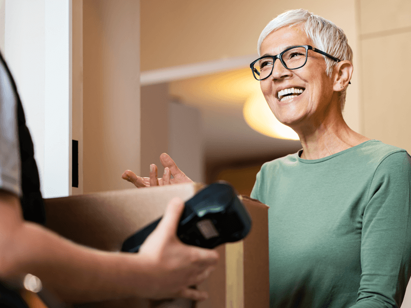 boxed mail package being delivered to visibly excited customer in doorway of apartment
