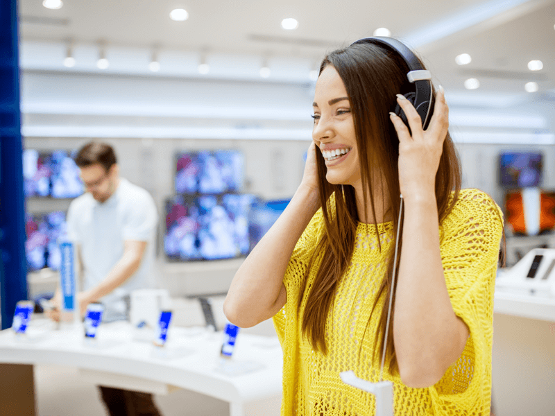 woman having a positive customer experience in a tech store listening to music through headphones