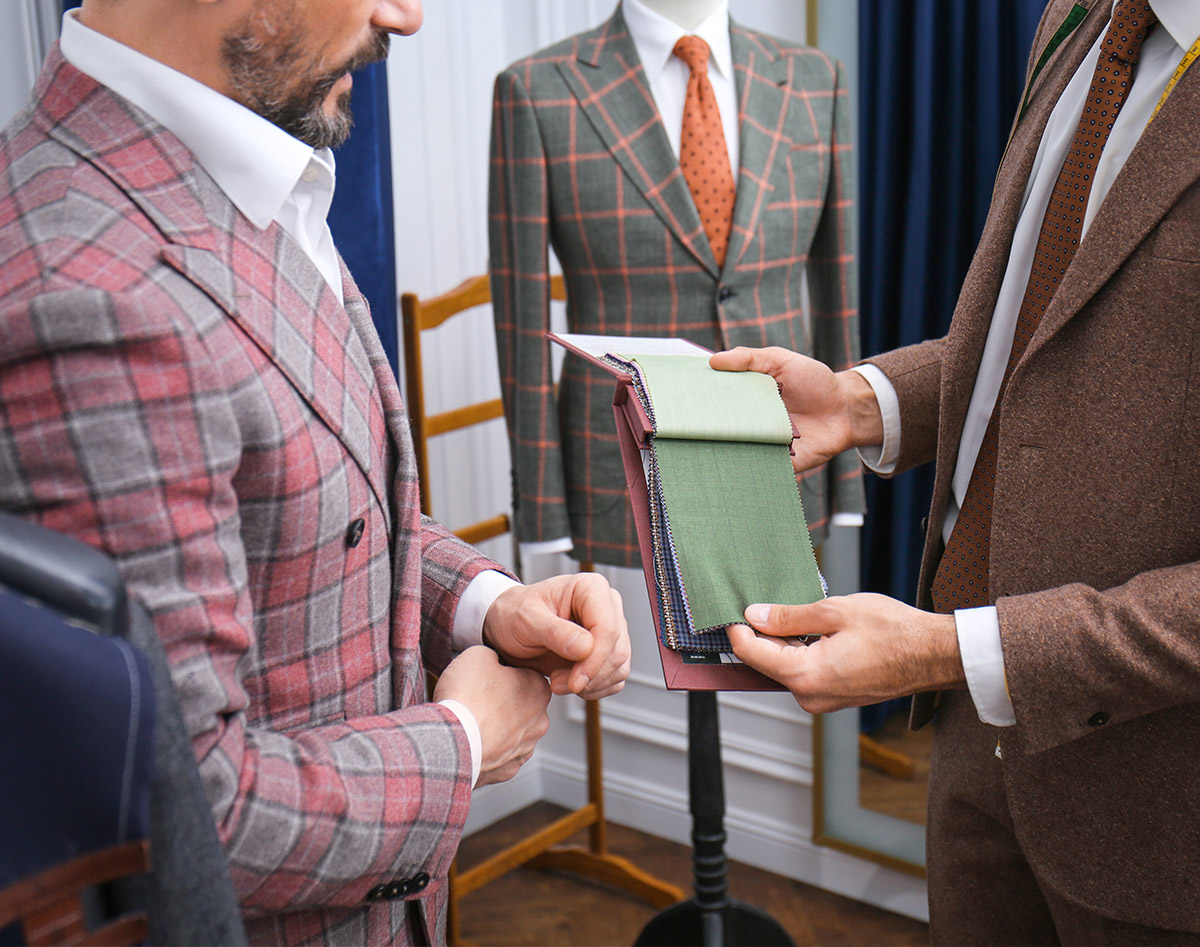 A salesperson shows a customer in a suit fabric swatches as content customized to the customer's fashionable style