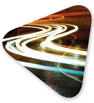 Swerving lines of bright light on a wet curved street at night