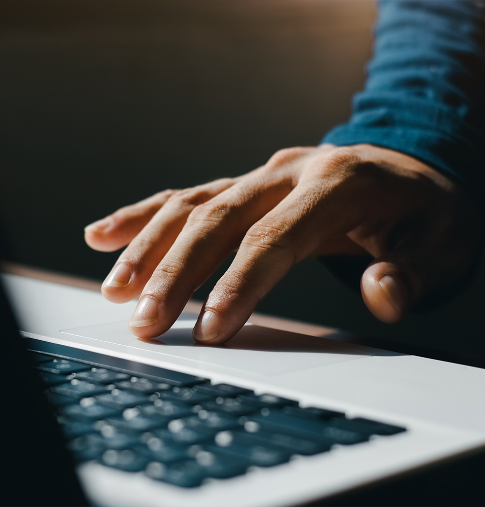 A close-up of a person's hand using the touchpad on a laptop keyboard.