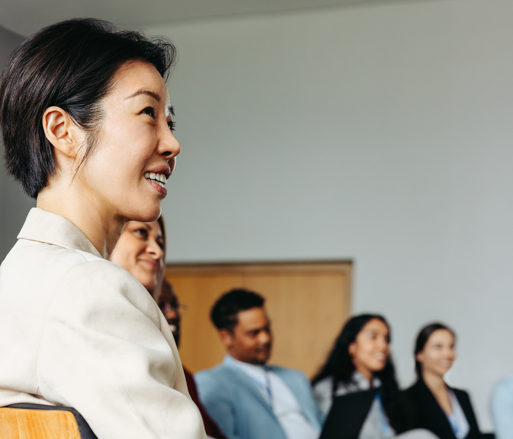 A group of people sitting in a conference room, listening to a presentation.
