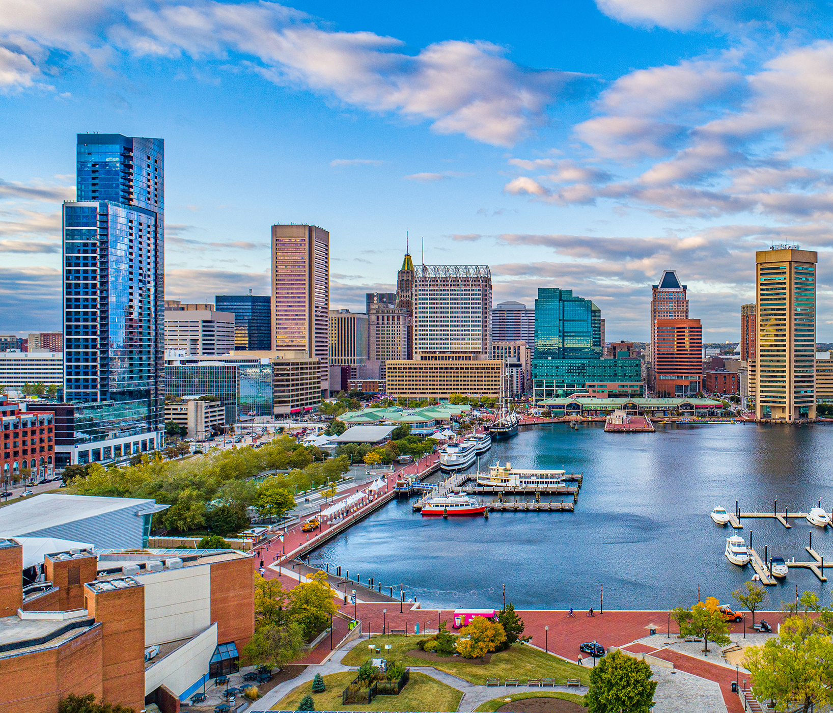 Baltimore's Inner Harbor with modern skyscrapers, waterfront buildings, and boats docked at the marina.