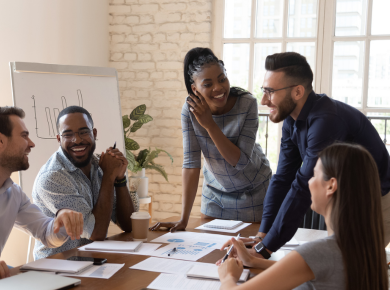a group of mixed race people working together in an office with a flipchart