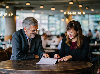Two people sit at a table in a coffee shop and compare notes on building resilience