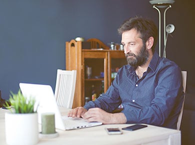 A man sits at his laptop and prepares for a video interview