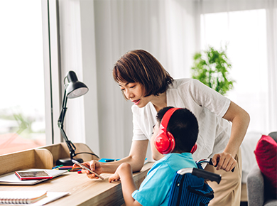 Female adult caregiver, assisting disabled student who is wearing bluetooth