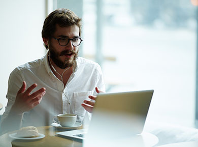 A man sitting at a table and having a virtual interview on his laptop