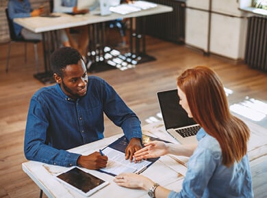 male and female sit across a table talking