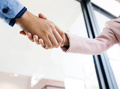 Two people shake hands after one prepares for a job interview