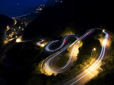 Curving road at night light up by headlights. Shifting smartly with data.