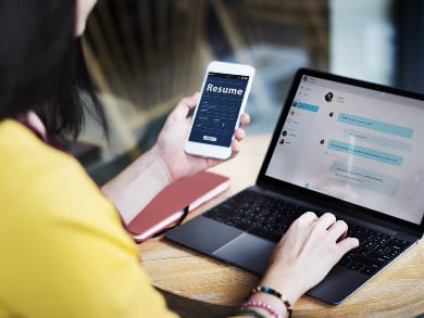 woman updating resume on mobile phone and laptop