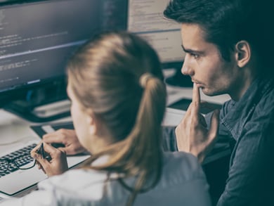 male and female review code on a computer