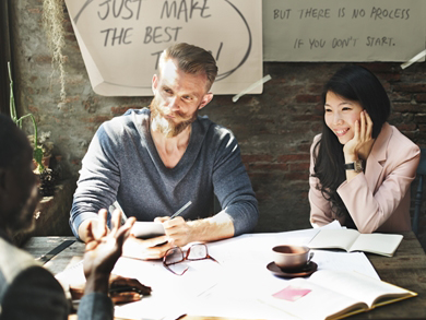relaxed, modern male and female sit at a table covered in papers