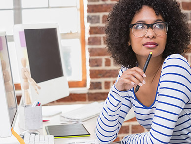 young professional woman in thought at her desktop computer