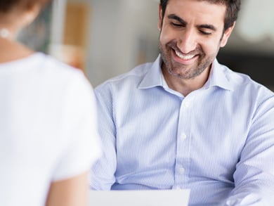 male recruiter analyzing and smiling down at resume