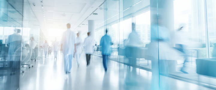 Blurred hospital corridor with people walking through a bright healthcare facility.