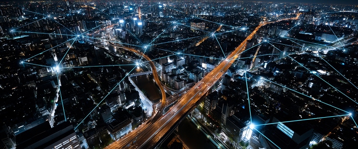 Aerial cityscape at night with glowing data lines overlaying buildings and streets.