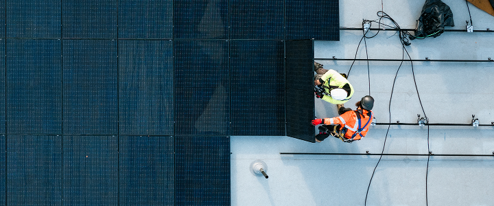 An overhead view of two utility workers performing maintenance on solar panels
