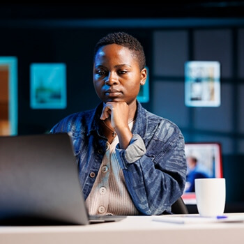 Person reviewing AI data on a laptop at a desk with a coffee mug.
