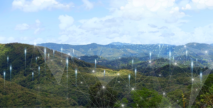 Scenic landscape of green forested hills under a partly cloudy sky, overlaid with a digital network graphic featuring glowing points and connecting lines, symbolizing the integration of artificial intelligence and technology within natural ecosystems