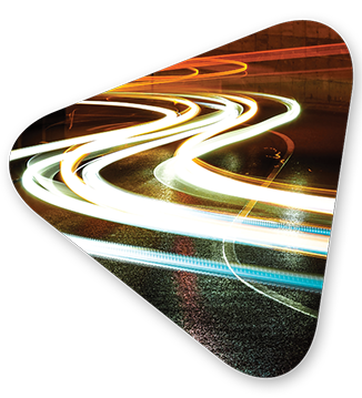 Swerving lines of bright light on a wet curved street at night