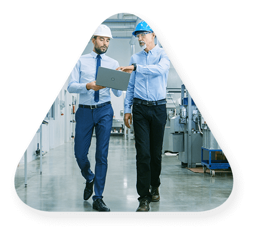 Two men with hardhats discuss what a laptop is showing