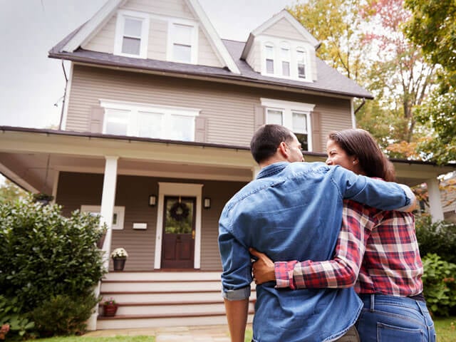 a couple standing outside of their house