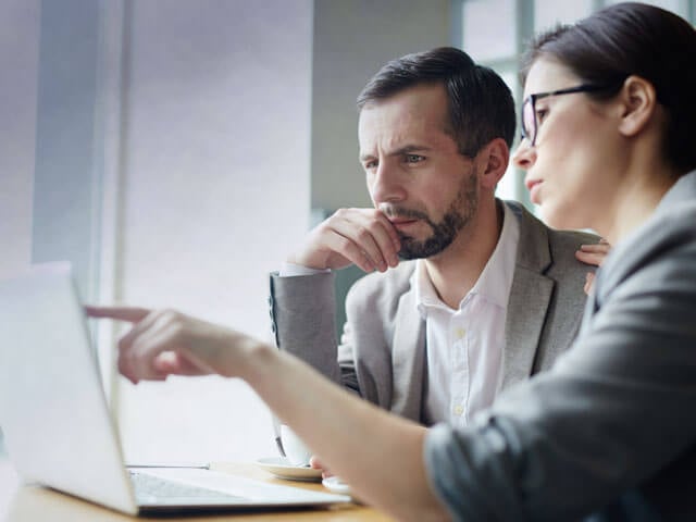 Two sales professionals discussing something on a laptop
