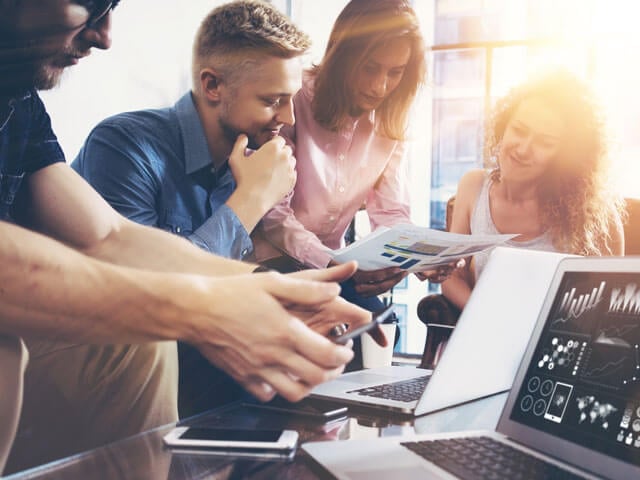 People gathered around computers and studying charts based on data from Salesforce Marketing Cloud