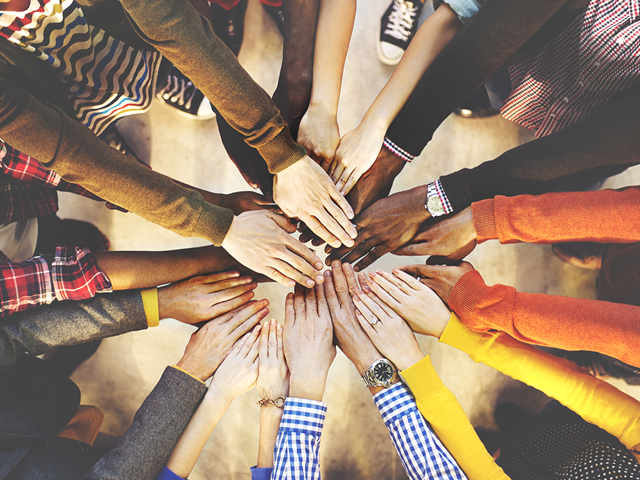 Group of people putting their hands together to symbolize teamwork