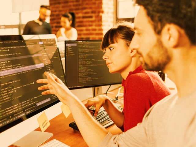 Digital customer experience team reviewing code on a computer