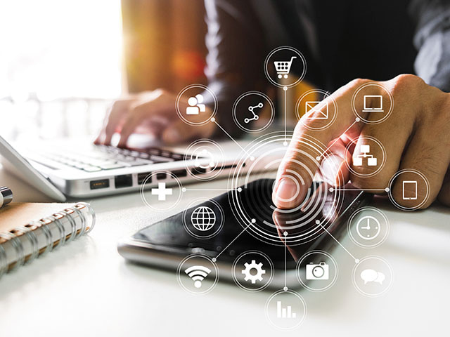 A person on a laptop taps a smartphone overlaid with a network of icons showing pandemic-era digital transformation