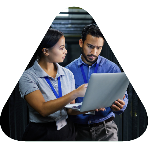 man and woman reviewing data on a laptop in the server room.