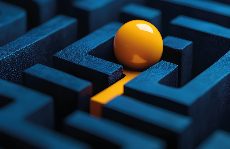 Close-up of a dark blue maze with an orange ball inside.