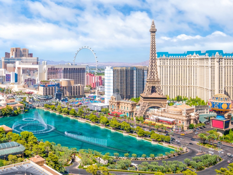 Aerial view of the Las Vegas Strip with hotels, fountains, and city landmarks.