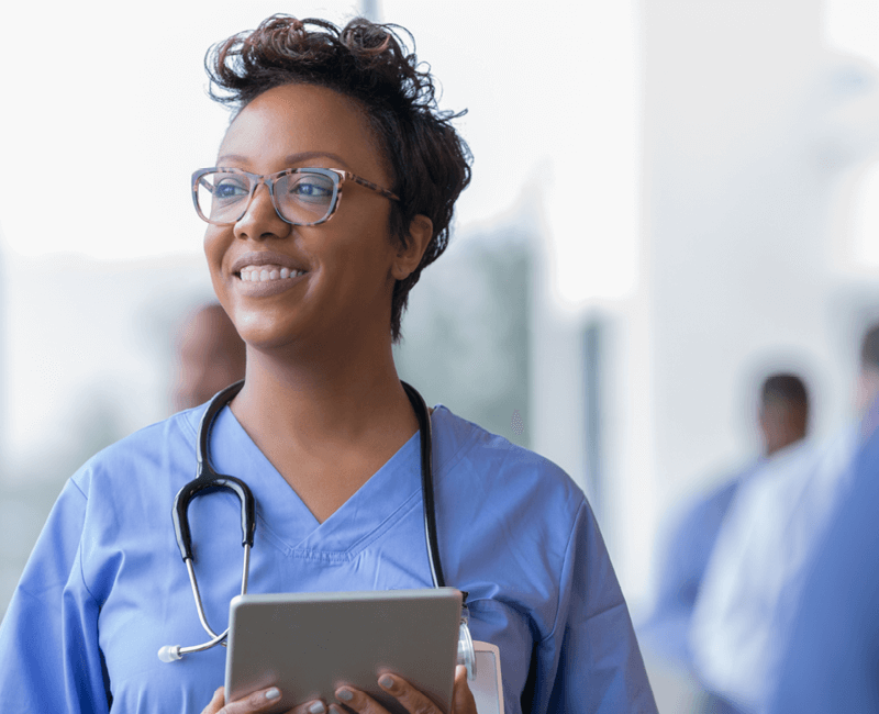 Medical professional dressed in blue scrubs holding tablet