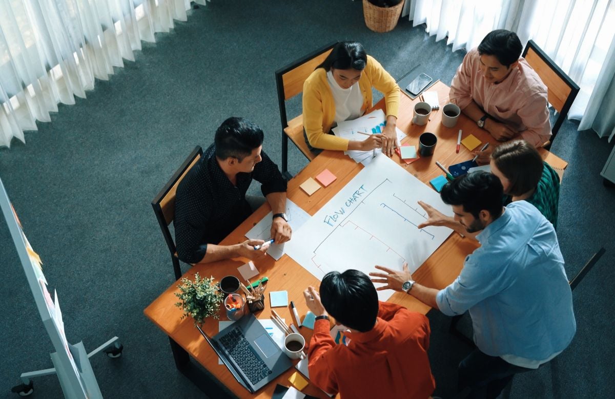 five professionals collaborating around an table in an office with windows