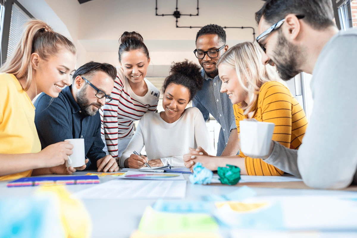 group of creative professionals huddled around a drawing table collaborating