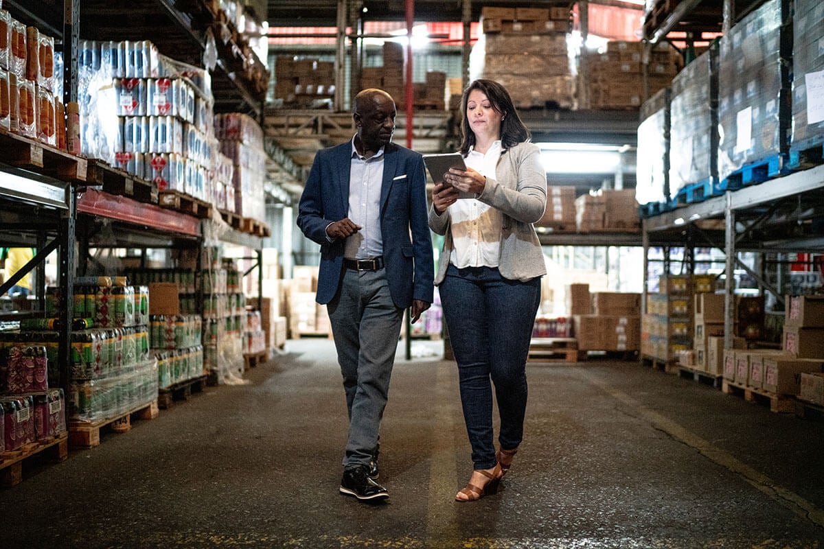 Two people looking at the iPad while walking in the warehouse