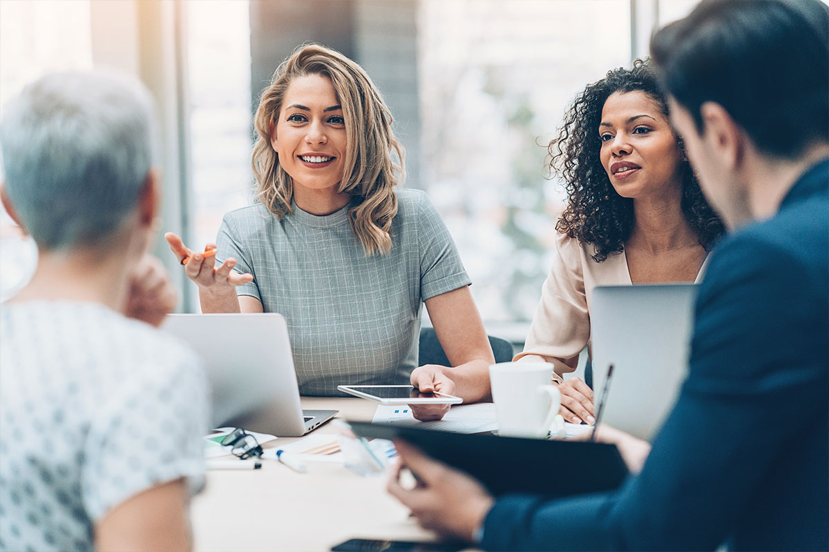 Business meeeting with four people seated around a table.