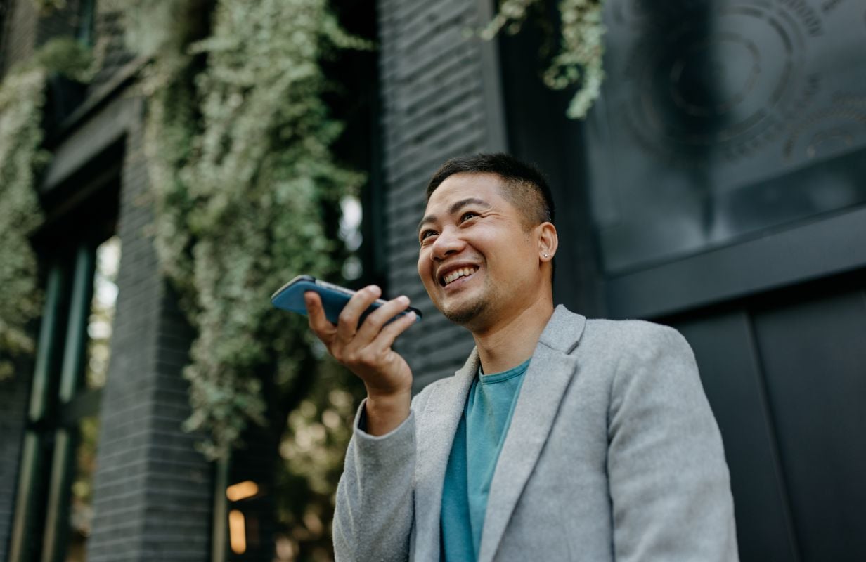 man smiling as he speaks to an ai agent on speaker phone