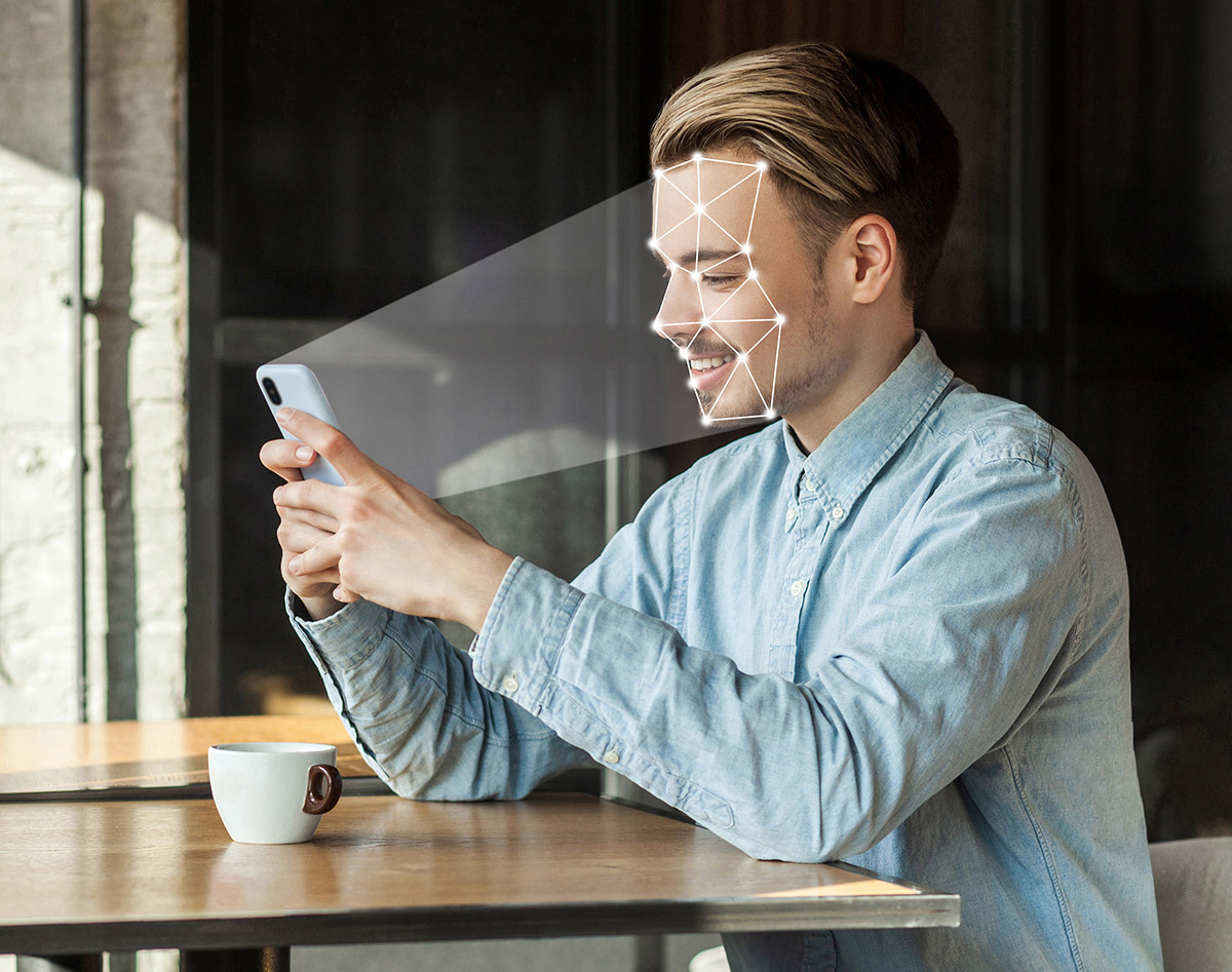 A man sits holding his phone as it scans him to determine how to personalize content for its target audience