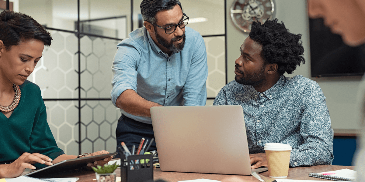 A team in a meeting room going over what is being displayed on a laptop