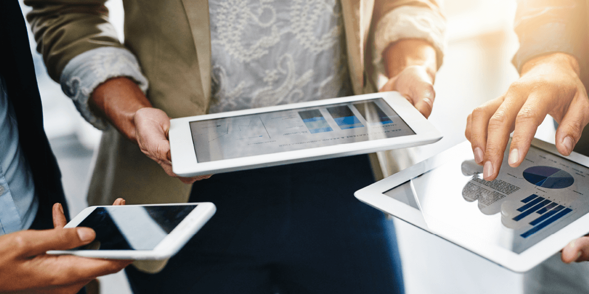technology enablement applications displayed on tablets held by three professional individuals.