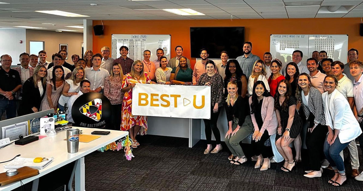 TEKsystems employees standing around a banner for the Best U program