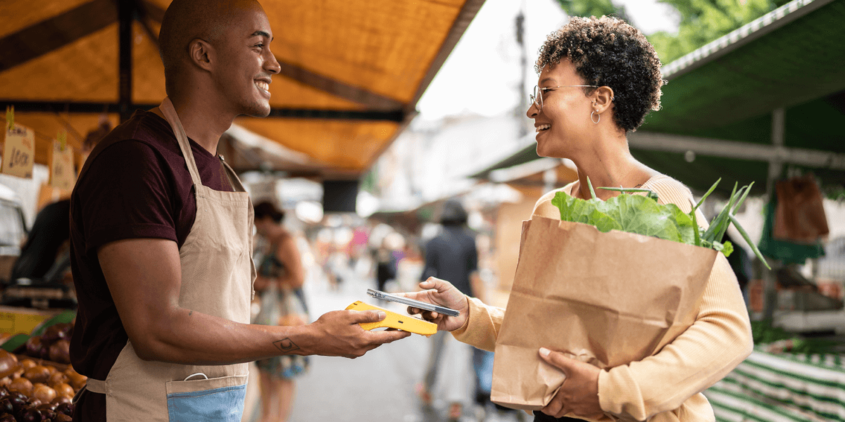 A woman carrying groceries paying with her phone